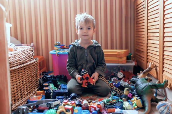 Kind umgeben von vielen Spielsachen